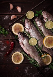 Raw rainbow trout, with lemon and herbs, on a wooden table, no people