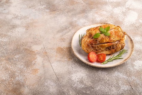 Fried Turkey Thigh with spices and rosemary on plate on brown concrete background. side view, copy