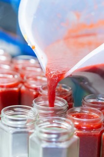 Liquid strawberry mass is filled from a cup into jars, jam production, Haselstaller Hof, Wildberg