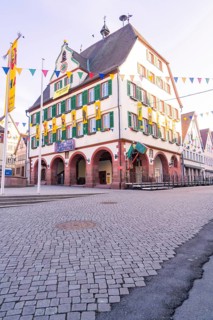 Historic half-timbered house on the market square with strong green shops and colourful flags along