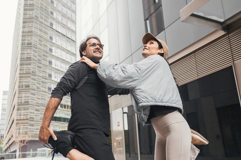 A fit couple enjoys a stretching session together in an urban environment. Their activewear