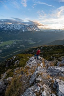 View of Wetterstein mountains with Zugspitze, mountaineer at the summit of Kramerspitz, at sunset,