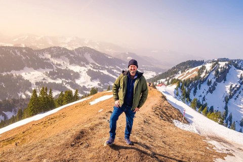 Person standing on a mountain under a clear sky with a view of the snowy landscape, Hochgrat