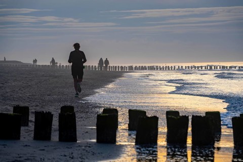 Winter on the North Sea, sunset at the beach, joggers, beach walkers, coastal protection, through