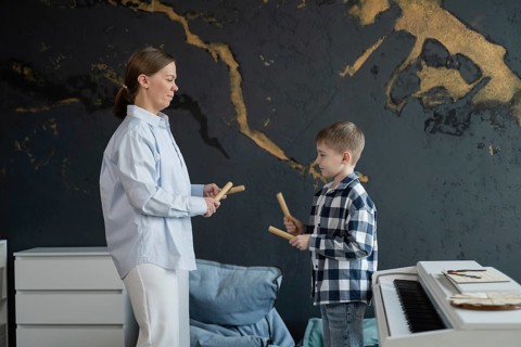A teacher is guiding a young student in a music lesson inside a stylish studio. The piano in the