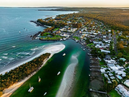A stunning aerial view of a coastal town with a winding river, pristine beach, lush greenery, and