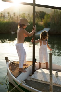 Siblings, a boy and a girl, play together on a boat in Andratx, Mallorca. They are both dressed in