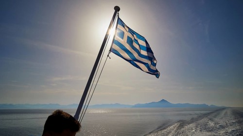 Greek flag waving in the wind, over the sea in sunny weather, crossing Rhodes to Symi, ferry, Symi,
