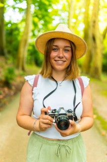 Vertical portrait of a smiling caucasian female traveler enjoying taking pictures during holidays