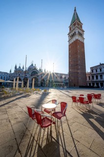 Chairs and tables of cafes, St Mark's Square in the morning light, St Mark's Basilica and