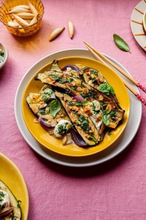 Top view of a colorful dish featuring roasted courgettes topped with mozzarella, basil, toasted