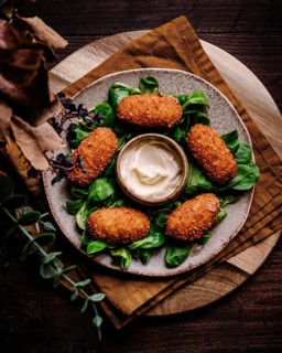 A high-angle view of crispy golden croquetas elegantly arranged on a rustic plate, garnished with