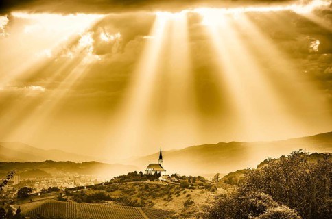 Sun rays shining down on a Church. Sepia color. Slovenia