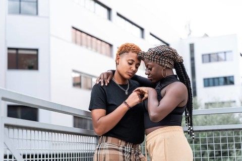 A loving LGBT multiethnic couple shares a tender embrace outdoors against a modern architectural