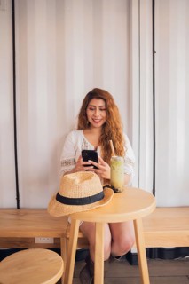 Young American Latin woman relaxing in a cafe, sipping a refreshing drink, and smiling while