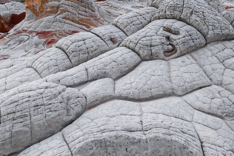 A captivating geological formation showcases abstract white rocks with striking red layers,