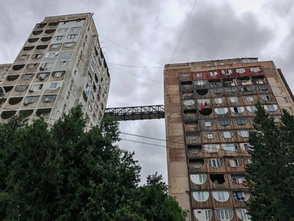 Two tall residential buildings with a bridge as a connection in a dramatic atmosphere in a wooded