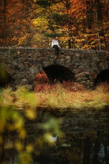 A serene moment captured on a stone bridge in Quebec during autumn, as vibrant fall colors of