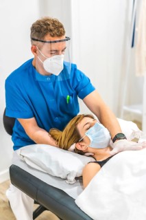 Structural osteopathy of a physiotherapist with protective measures for a patient on the stretcher.