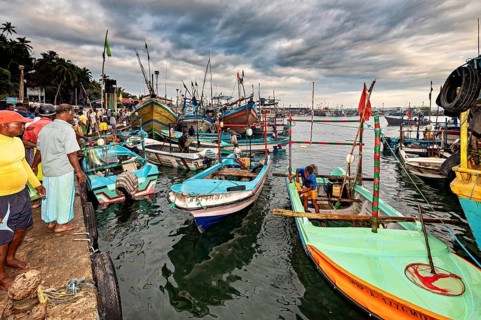 Fishing boats in busy harbor with people and dynamic clouds in the sky, The fishermen at Matara