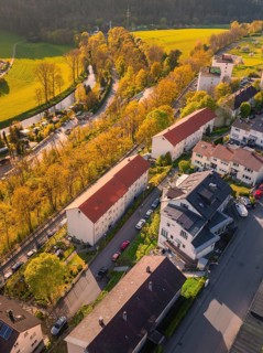 Residential buildings in a sunny urban landscape with streets, cars and neighbouring fields,