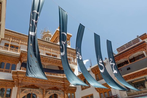 The Jamia Masjid Leh stands tall, adorned with striking turquoise banners that sway gracefully.