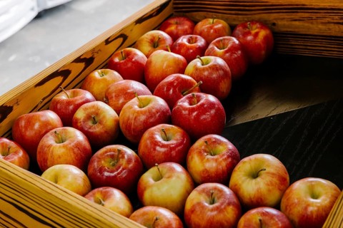 A rustic wooden box filled with fresh red apples is neatly arranged, creating a pleasing visual