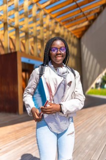 Vertical portrait of an African young woman standing outside the university smiling at camera