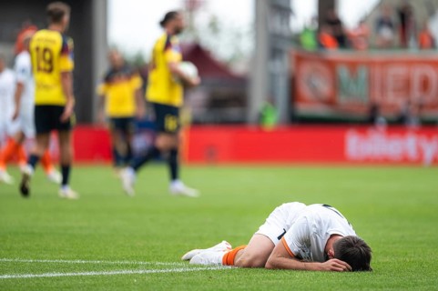 The injured footballer lies on the pitch