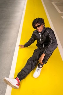 Vertical photo of a cool african artist man sitting on a garage