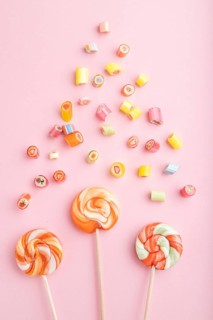 Various caramel candies on pink pastel background. close up, top view, flat lay