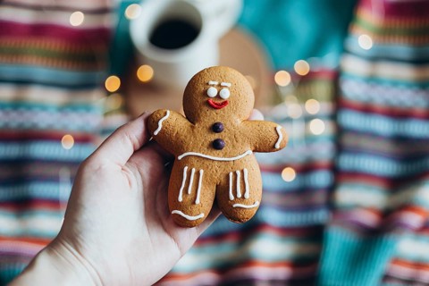 A close-up of a charming gingerbread man cookie held in hand, showcasing intricate icing details,