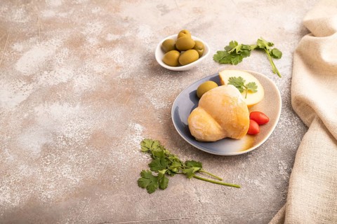 Smoked Mozzarella cheese, with tomatoes and olives on brown concrete background and linen textile,