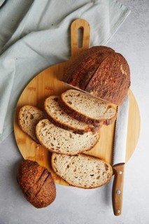 Top view of fresh homemade bread on a wooden cutting board, featuring slices of crusty sourdough