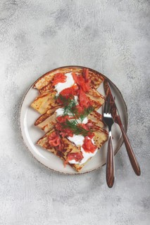 Delicious pancakes with salmon and sour cream, breakfast, on a plate, rustic style, with cutlery
