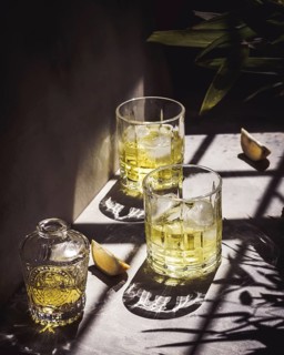 Aesthetic composition of lemon liqueur with ice cubes in glasses casting intricate shadows in the