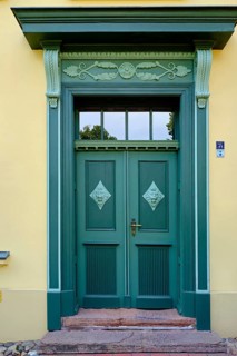 Richly decorated historic front door in green with the house number 34 next to it, concept of