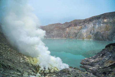 Dense sulfuric steam ascends from the turquoise crater lake of Ijen volcano in Indonesia, creating