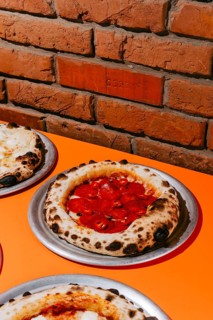 Wood-fired pepperoni pizza topped with salami, mozzarella, tomato sauce, and chili pepper. Served