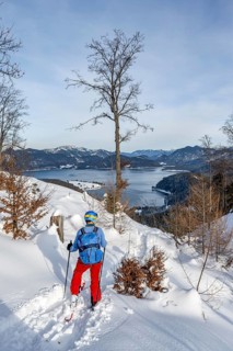 Skiers skiing down the Simetsberg, view of Walchensee and mountain panorama, Estergebirge, Bavarian