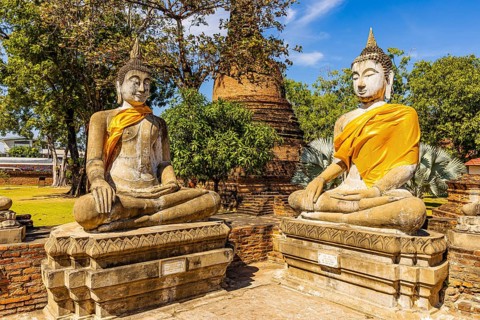 Stone Buddha statues decorated with yellow cloths, historic Buddhist temple complex, Ayutthaya,