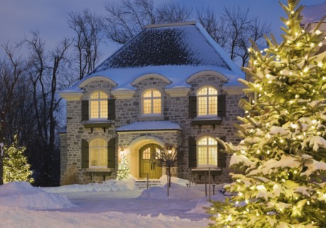 Luxurious residential cottage style home with illuminated evergreen trees at dusk in winter, Quebec, Canada