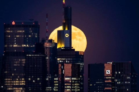 The full moon passes behind the Frankfurt banking skyline, Frankfurt am Main, Hesse, Germany