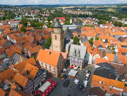 Drone shot of a historic town centre with a church, half-timbered houses and a lively market