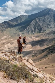 Traditional Kyrgyz eagle hunter hunting in the mountains in a dry landscape, near Kysyl-Suu, Issyk