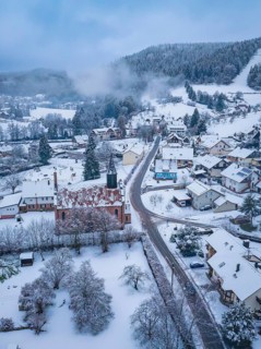 Aerial view of a snowy village with church and winter landscape, quiet atmosphere, Enzklösterle,