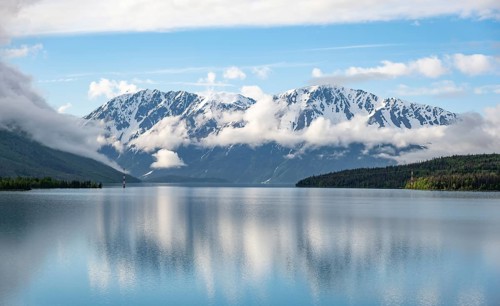 Snowy mountains in spring are reflected in turquoise blue Kenai Lake, Cooper Landing, Kenai