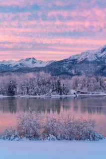 Dawn and sunrise at the wintry Forggensee in a snow-covered winter landscape in the foothills of