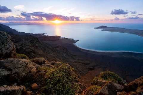 View from steep cliffs to sea and coast with sun stars, Mirador del Porrito viewpoint at sunset,