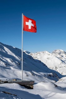 Swiss flag in front of mountain landscape in winter, mountain panorama with the peaks of the